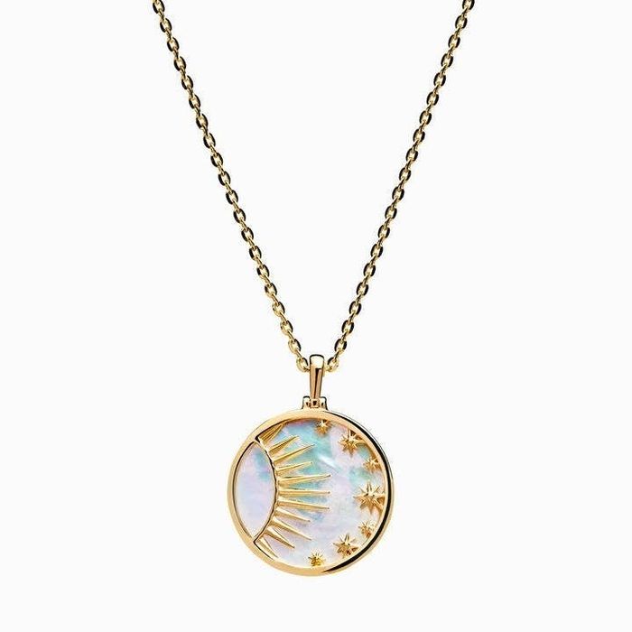 A gold circle necklace with a mother of pearl background, featuring a raised sun and moon design inside.