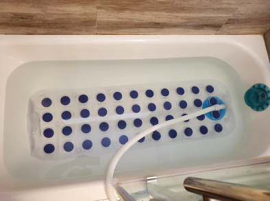 A reviewer's bath showing the bubble massage mat suctioned to the bottom of the tub.