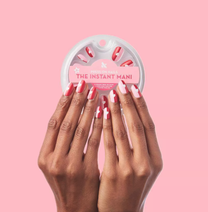 A model showcasing press-on nails that are split between pink and red, with a charming white heart in the center
