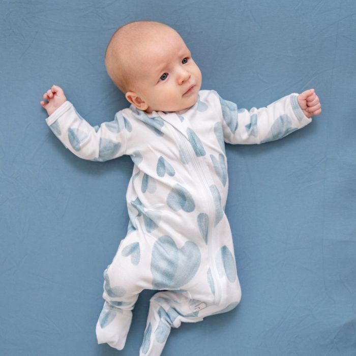A baby wearing sleeper pajamas decorated with blue hearts.