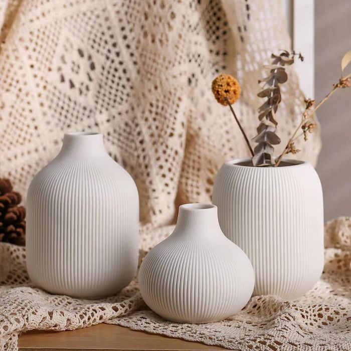 the three vases placed on a table, one featuring flowers inside