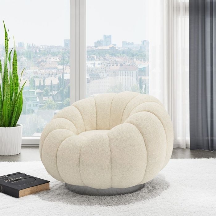A cozy, round white armchair sits on a soft carpet in front of a large window showcasing a city skyline. A potted plant adds a touch of greenery nearby.