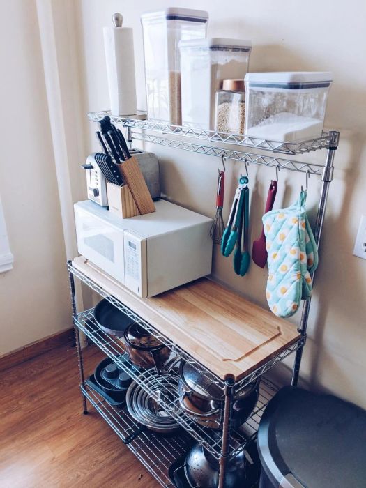 A reviewer’s photo of the rack with pots on the bottom, a microwave in the middle, and flowers and sugar on top, still leaving room to prep meals.