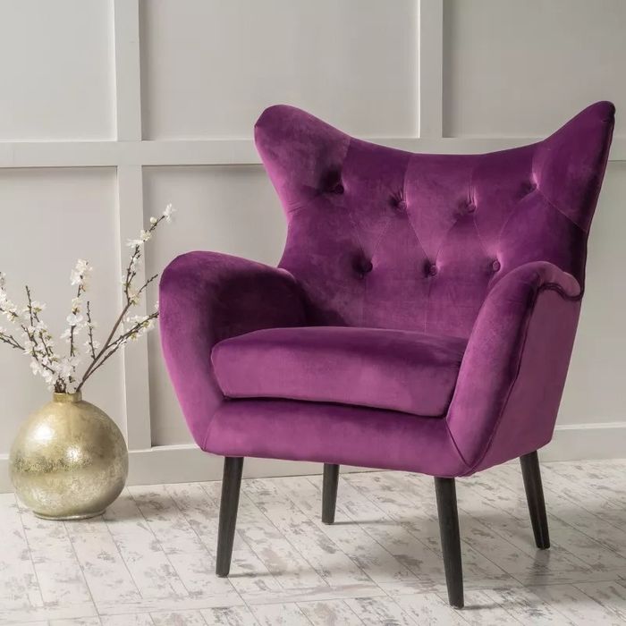 A modern tufted wingback chair placed in a cozy home setting, complemented by a decorative vase