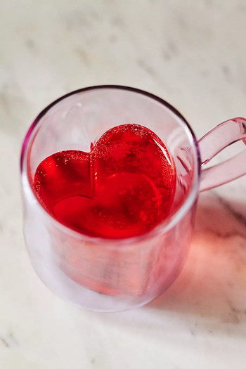 A lilac glass mug with a heart-shaped design inside.