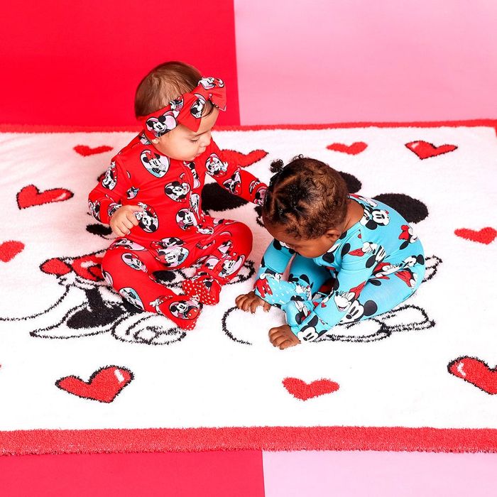 Two babies lounging on a plush Mickey and Minnie Mouse Valentine's Day blanket.