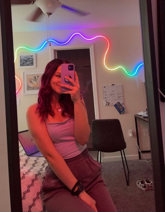 reviewer with a rainbow neon rope light glowing in the background