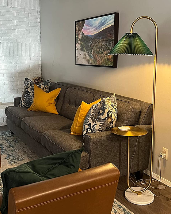 a gold floor lamp with a green shade in a reviewer’s living room setting