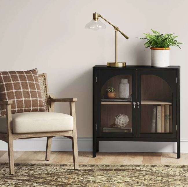 A modern armchair next to a black cabinet adorned with decorative items and a lamp, offering home interior inspiration