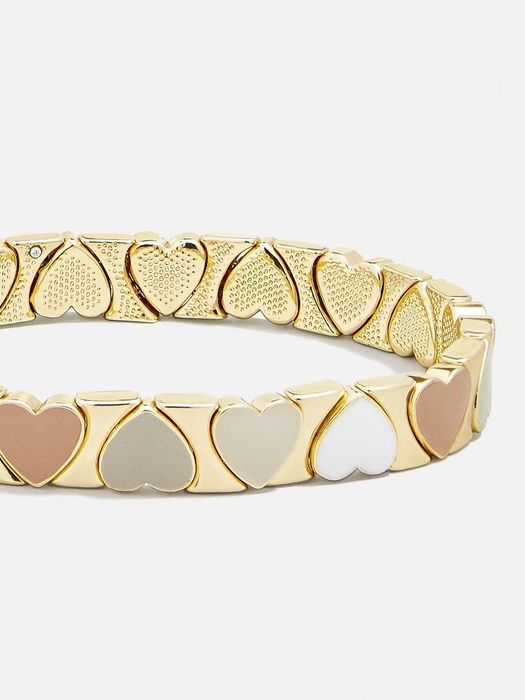 A gold bracelet with neutral-colored enamel hearts that wrap around it