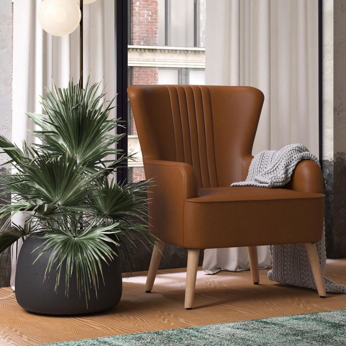 The caramel faux-leather chair with angled legs and a tall backrest.