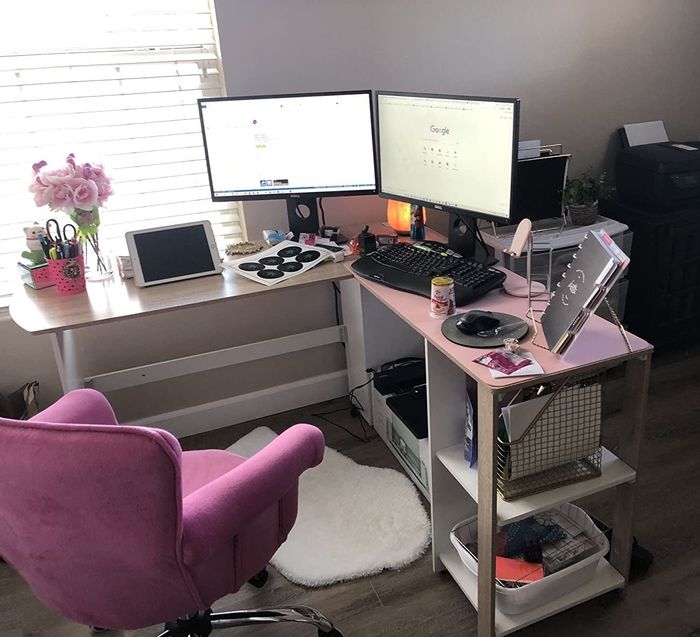 Reviewer's light wood and white desk featuring two storage shelves, positioned next to a pink chair and a white area rug