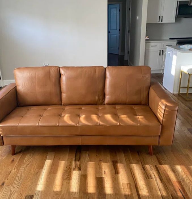 long brown leather tufted couch in a cozy living area