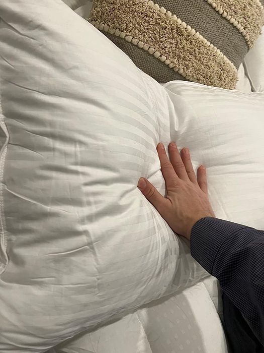 a reviewer pressing their hand into a soft, plush pillow