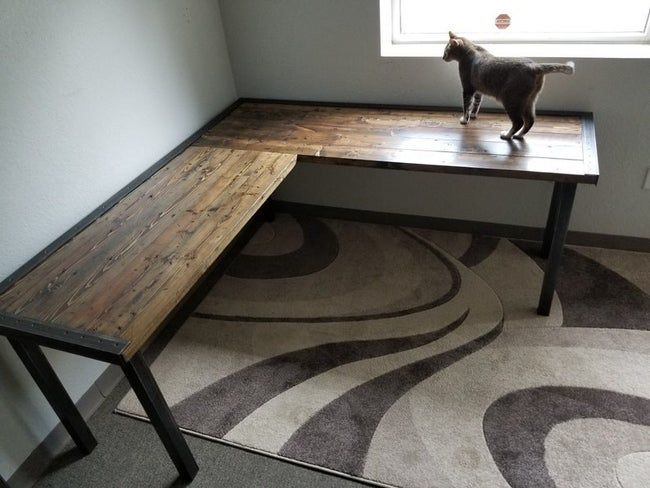 Wood and black L-shaped desk with a cat perched on top