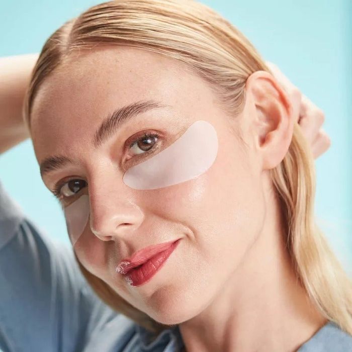 A person with under-eye patches, casually posing with one hand behind their head
