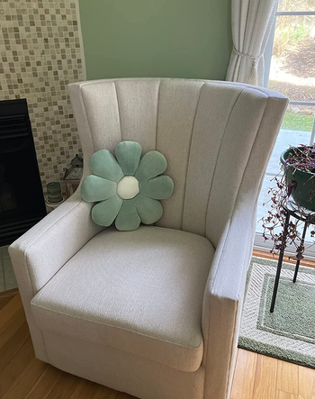 Blue daisy-shaped pillow resting on the reviewer's armchair
