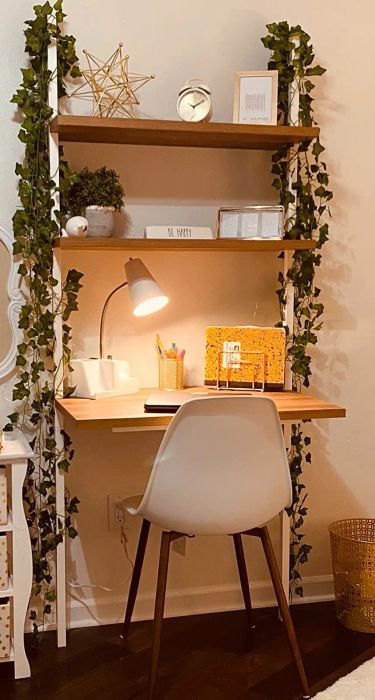 A three-tier storage desk mounted to the wall, adorned with faux vines on either side.