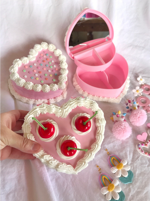 three heart-shaped cake jewelry boxes surrounded by earrings