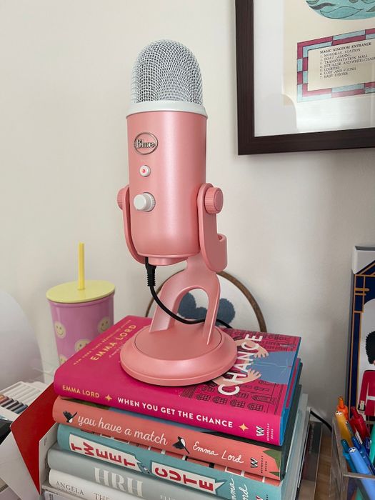 A pink microphone resting atop a stack of books