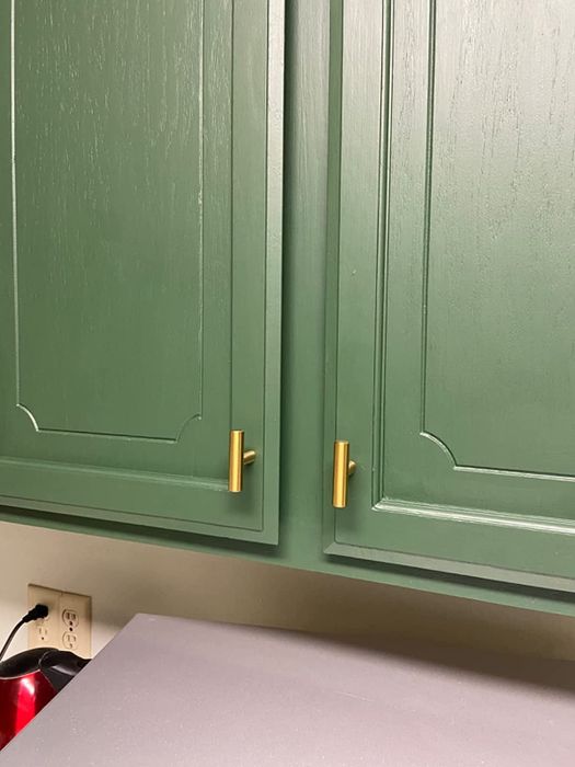 A green cabinet adorned with gold knobs