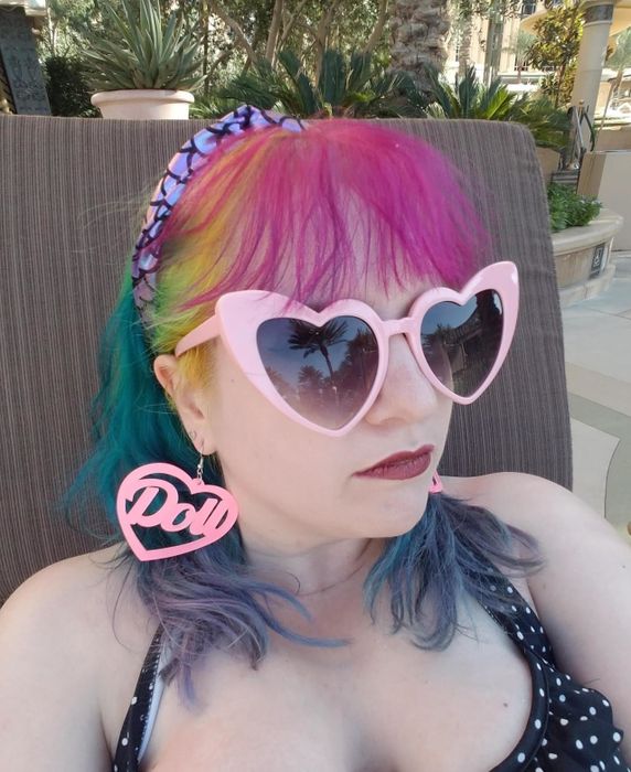 A reviewer wearing pink heart-shaped sunglasses.