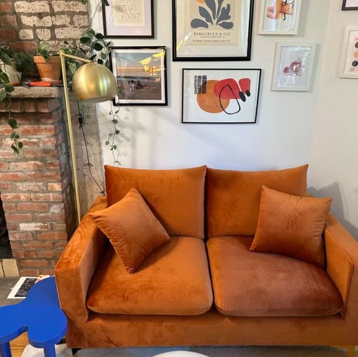 small orange velvet loveseat with two coordinating pillows