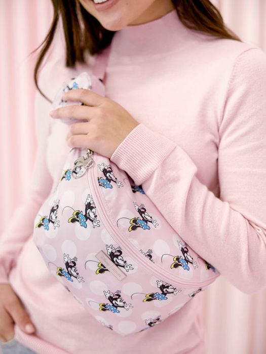 A model wearing a pink Minnie Mouse sling bag.