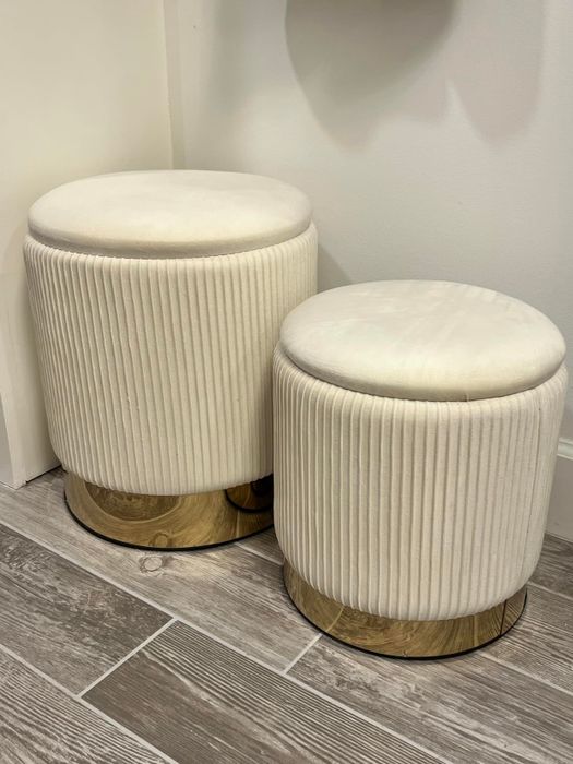 Two pleated velvet ottomans with wooden bases, placed on a tiled floor, ideal for modern home decor