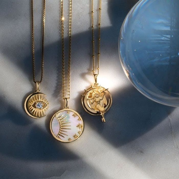 Three gold charm necklaces featuring celestial-inspired designs.