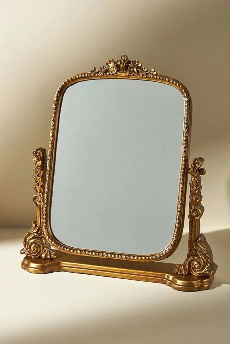 A gold vanity mirror, elegantly designed with a touch of vintage charm.