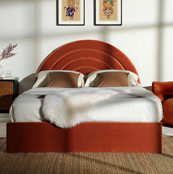 A modern bedroom featuring an arched velvet headboard, plush pillows, and a cozy textured blanket draped over the bed, adding a touch of luxury and comfort.