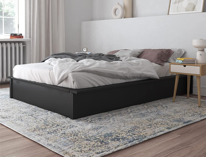 A lifestyle image of a black platform bed positioned in a cozy bedroom setting.