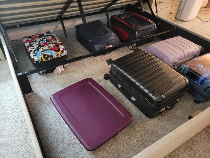 Suitcases and storage bins neatly tucked away under a bed, showcasing a smart use of available storage space.