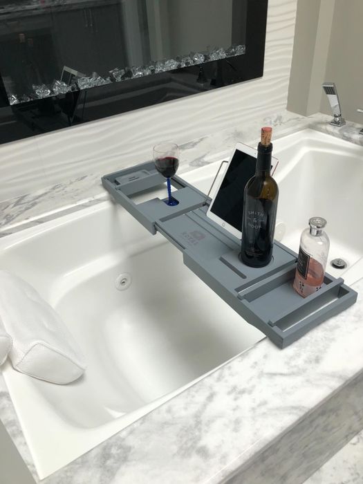 reviewer photo of a bath caddy with a bottle of wine and accessories placed on it