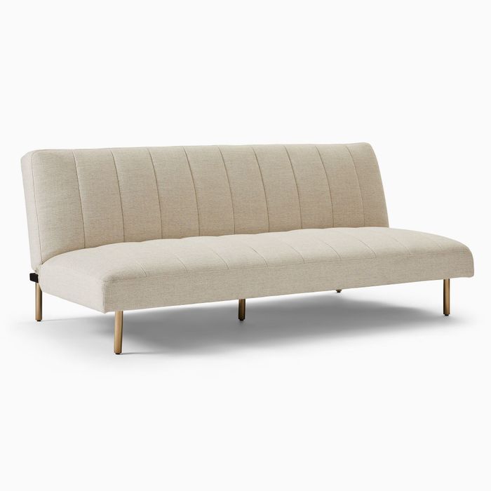 A modern beige futon sofa featuring vertical stitching on the backrest and sleek, slender metal legs, perfect for contemporary minimalist interiors.