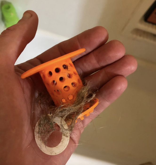 reviewer’s photo of the orange TubShroom filled with hair