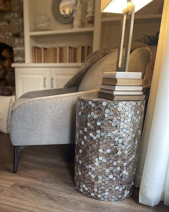 a reviewer photo showing the table in a living room, decorated with books and a lamp on top