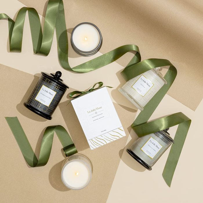 Candles and packaging displayed on a table surrounded by curled ribbon