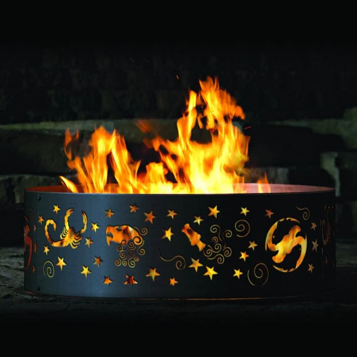 A striking black metal fire pit featuring intricate Zodiac designs cut into its sides.