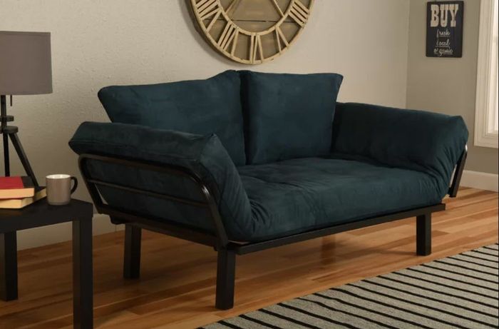 A velvet futon-style sofa resting on a sleek metal base.