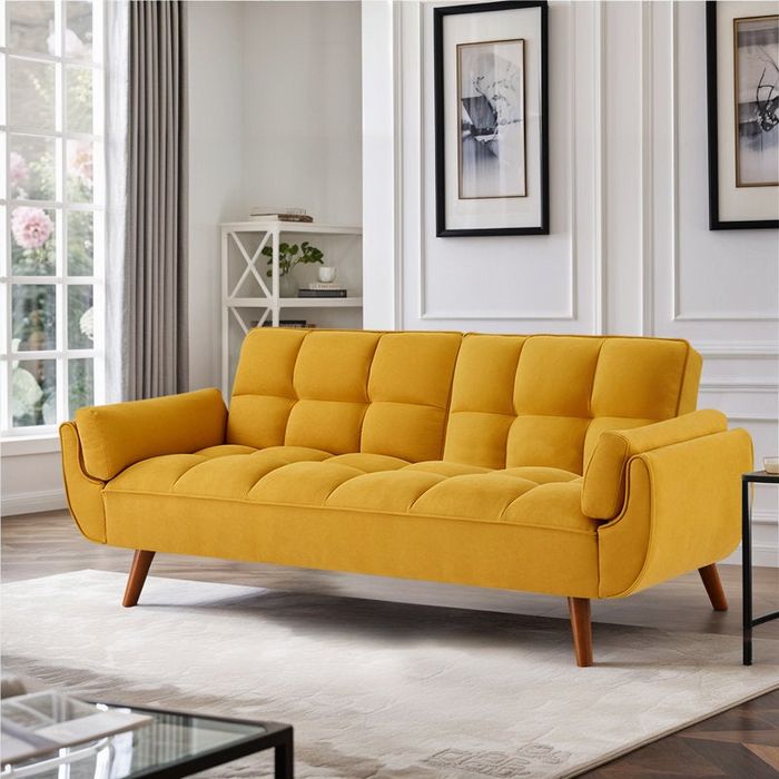 A modern sofa featuring tufted cushions and wooden legs, set in a bright and chic living room.
