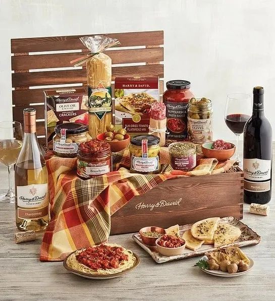 A gift crate displayed alongside freshly prepared Italian meals and two bottles of wine.