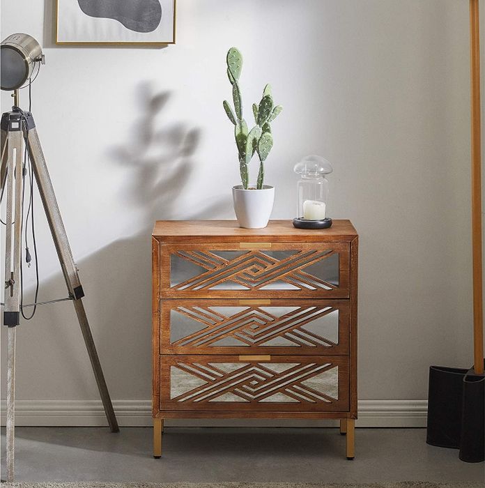 Lifestyle photo of a small mirrored dresser with a cactus on top