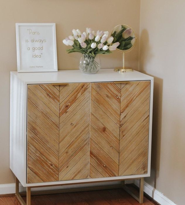Reviewer’s photo of the wood-paneled accent table with a vase of tulips, a framed print, and a mirror resting on top