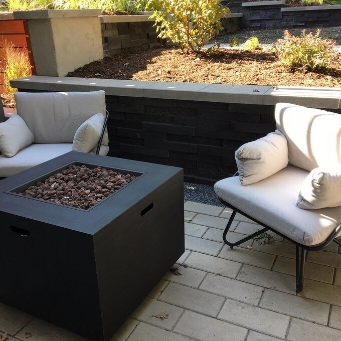 A stylish set of white patio chairs arranged around a reviewer’s fire pit, ready for a relaxing outdoor evening.