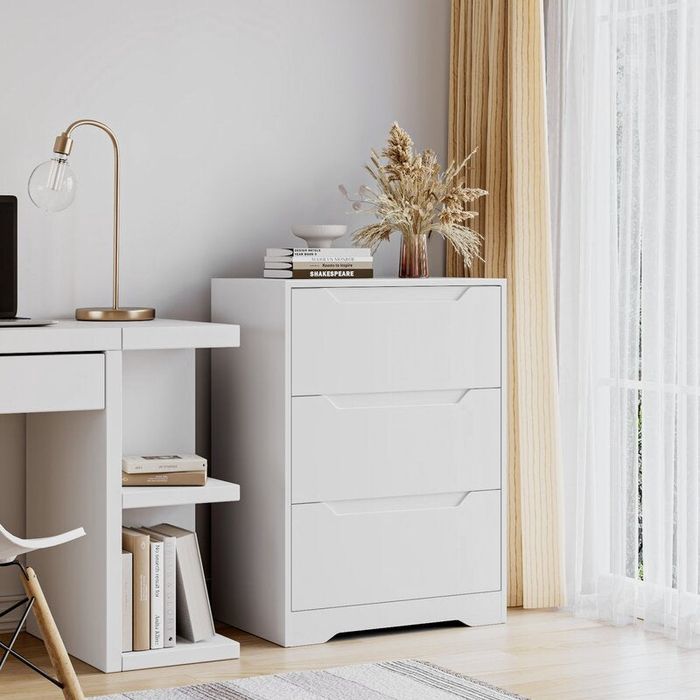 A white three-drawer dresser styled in a home office