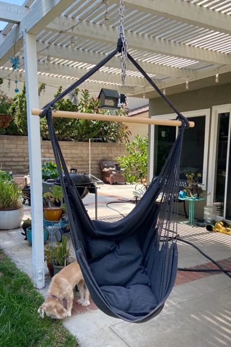 A reviewer showcases the dark gray hammock chair hanging from a pergola in their outdoor space.