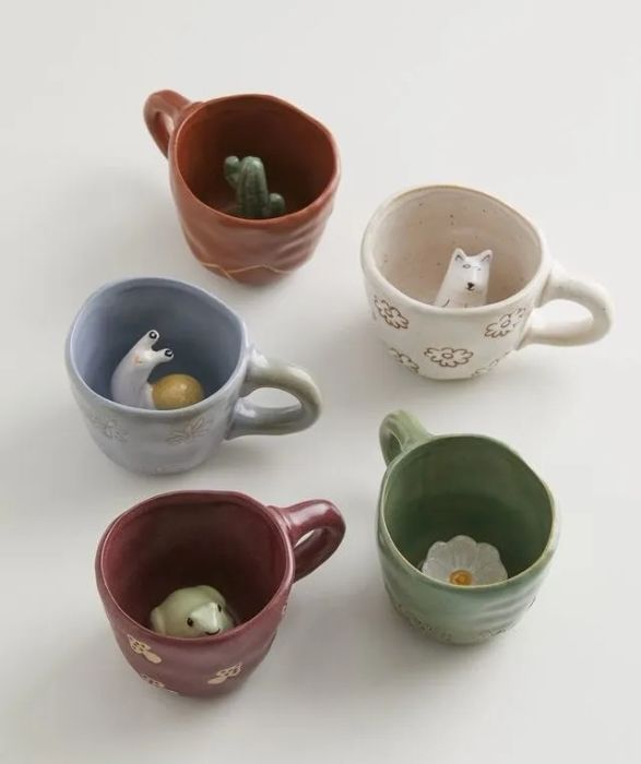 Five ceramic mugs with concealed critters and plants inside