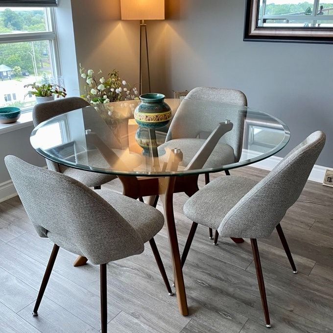 A set of elegant grey upholstered dining chairs arranged around a reviewer's dining table.
